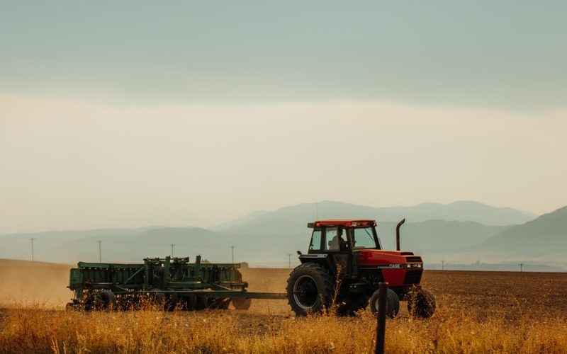 red and black tractor on brown grass field during daytime