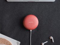 flat lay photography of coral Google Home Mini on black surface beside Apple AirPods