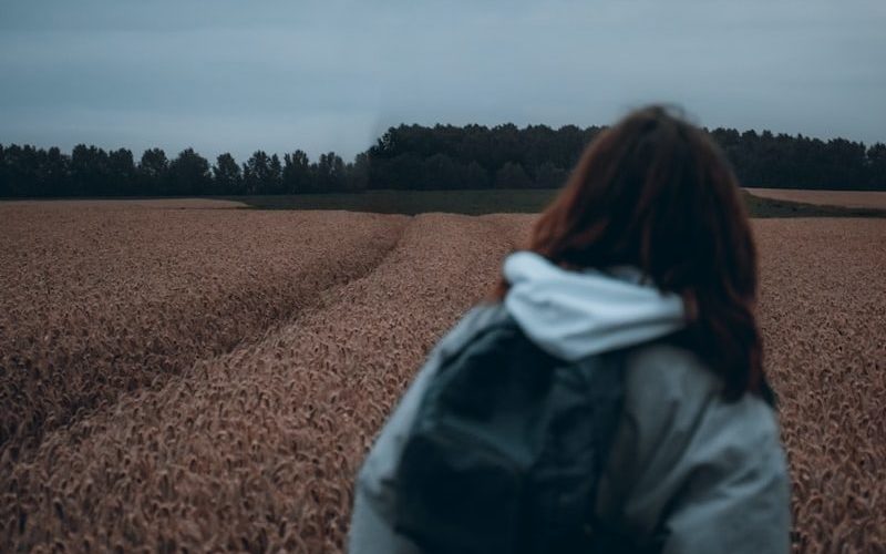 woman in black jacket standing on brown field during daytime