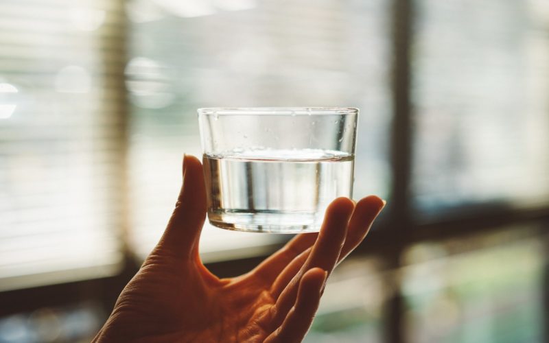 person holding clear glass cup with half-filled water