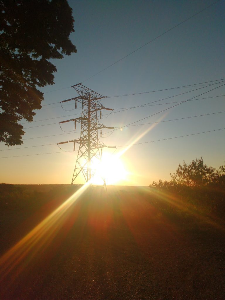 Imagem de por do sol, atrás de uma torre de transmissão