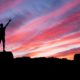 silhouette of man standing on high ground under red and blue skies