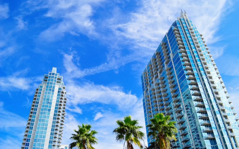 green palm trees near high rise buildings under blue sky during daytime