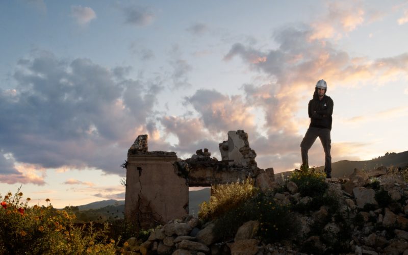 man standing on rock formation under cloudy sky during daytime