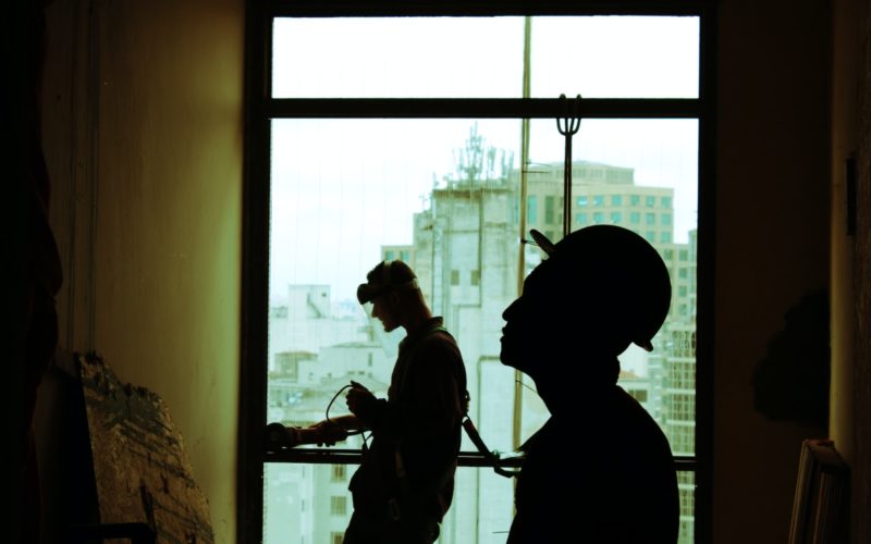 two men wearing hard hat standing near clear glass window